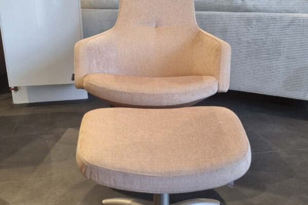 Moderner beiger Sessel mit Hocker auf schwarzem Boden