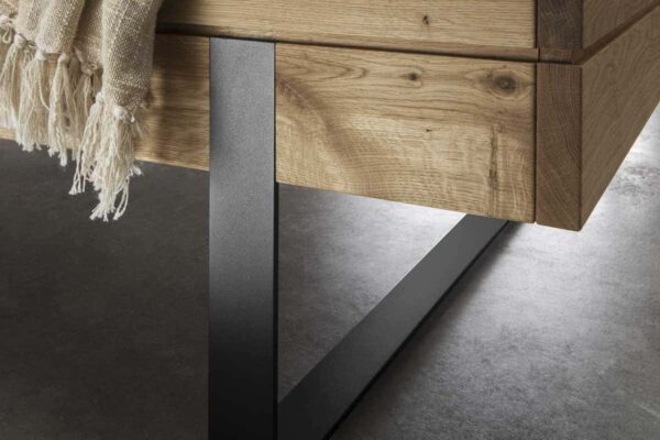 Nahaufnahme von Bettgestell aus Holz mit Metallbein auf Betonboden