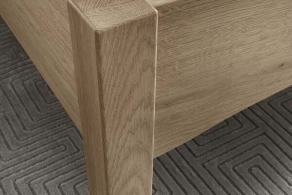 Eckige Holzfüße eines Bettrahmens auf geometrischem Teppich