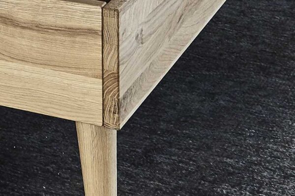 Holzbettgestell mit brauner Polsterung auf dunklem Teppich