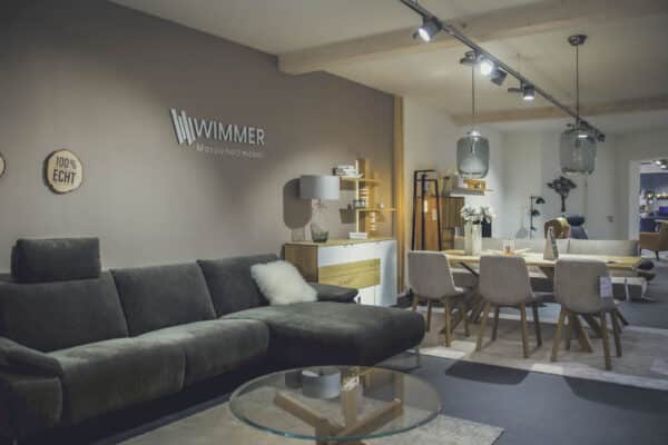 Modernes Wohnzimmer mit grauem Sofa und Essbereich von Wimmer Massivholzmöbel