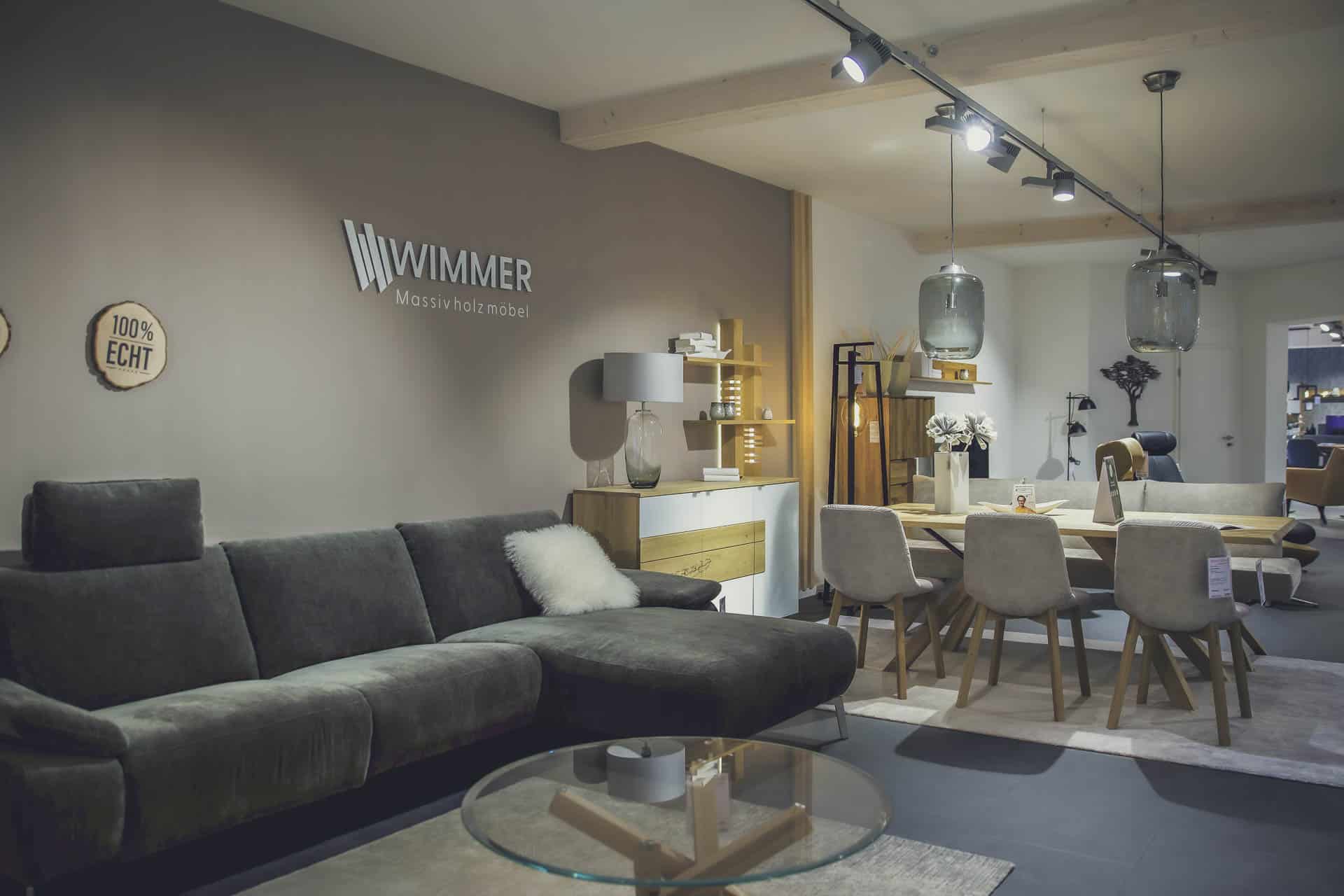 Modernes Wohnzimmer mit grauem Sofa und Essbereich von Wimmer Massivholzmöbel