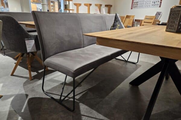 Graue Polsterbank mit Holzstühlen in modernem Showroom