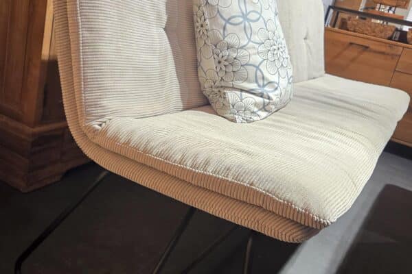 Beigefarbenes Sofa mit Blumenkissen vor Holzschränken im Wohnzimmer