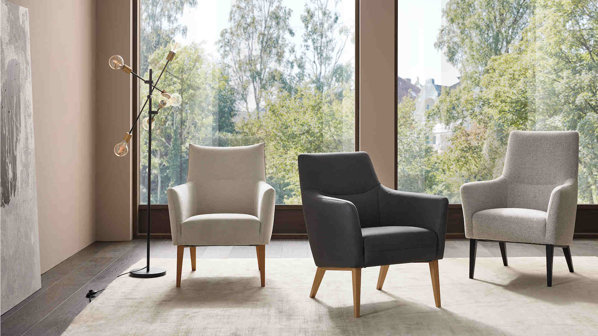 Moderne Wohnzimmer mit drei stilvollen Sesseln und Stehlampe vor großen Fenstern